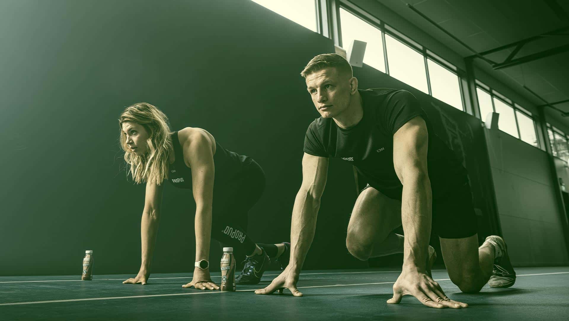 Photo of a man and a woman ready for a sprint with a ProPud chocolate milkshake next to them.