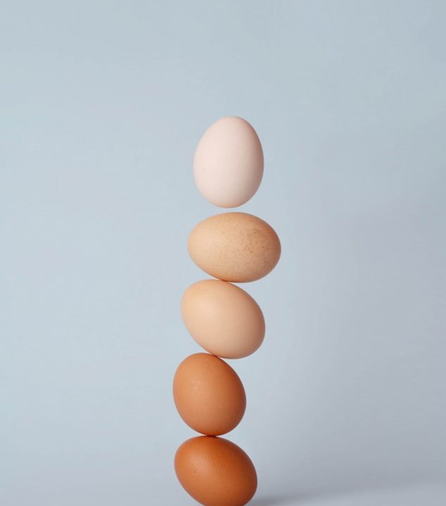 Photo of white and brown eggs balancing on each other.